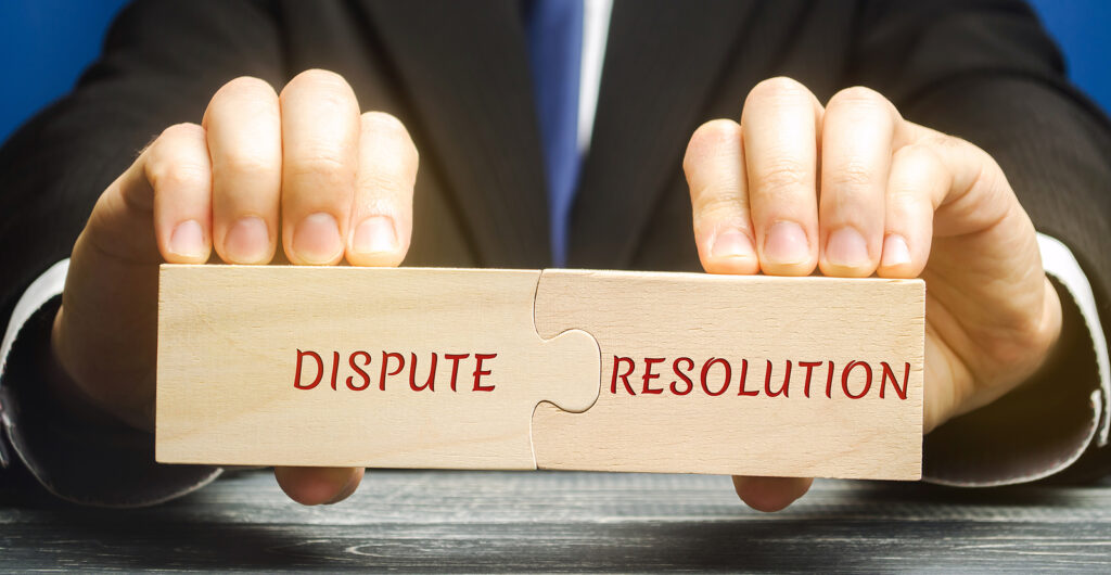 Man holds wooden puzzles with the words Dispute Resolution.